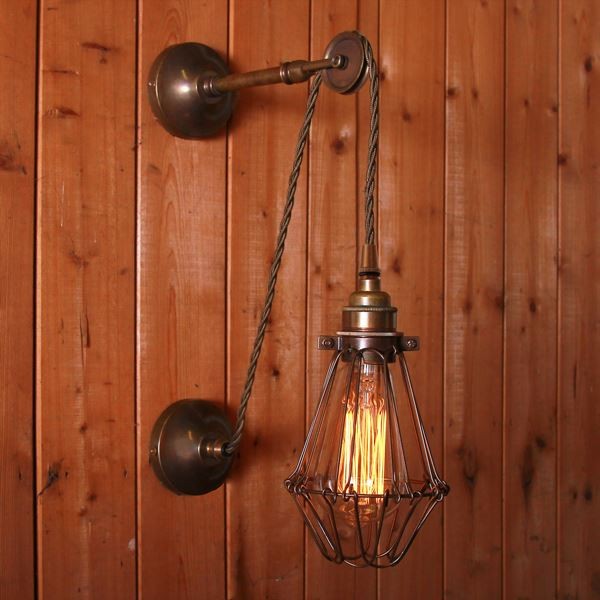 The Apoch cage wall light is an industrial style light with an exposed bulb protected by a striking brass cage. 