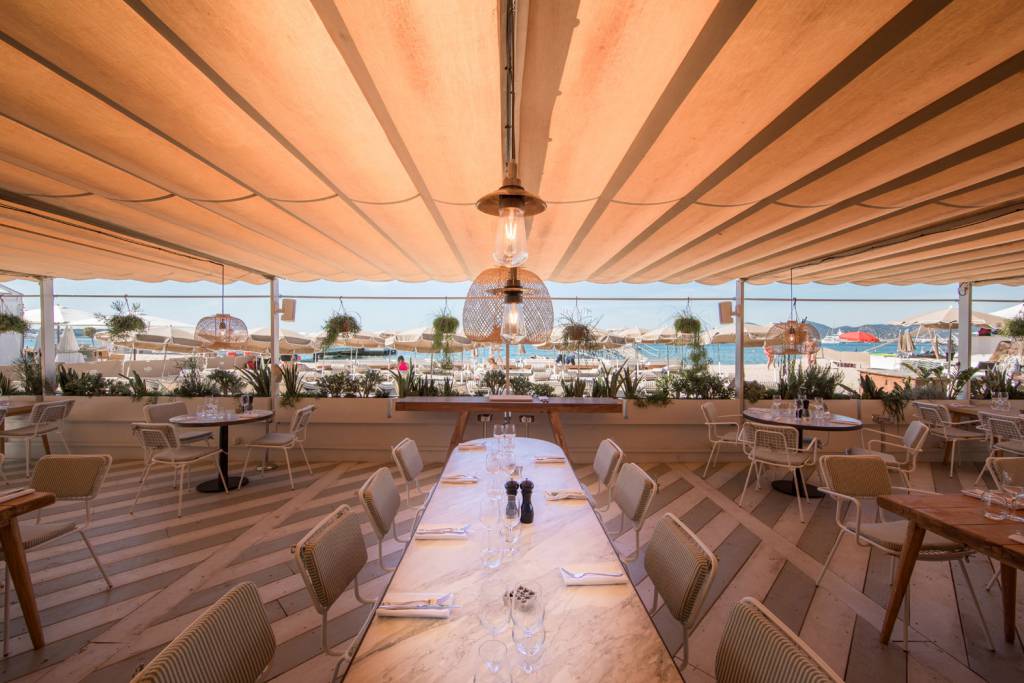 An antique brass shade echos the beautiful white marble dining tables 