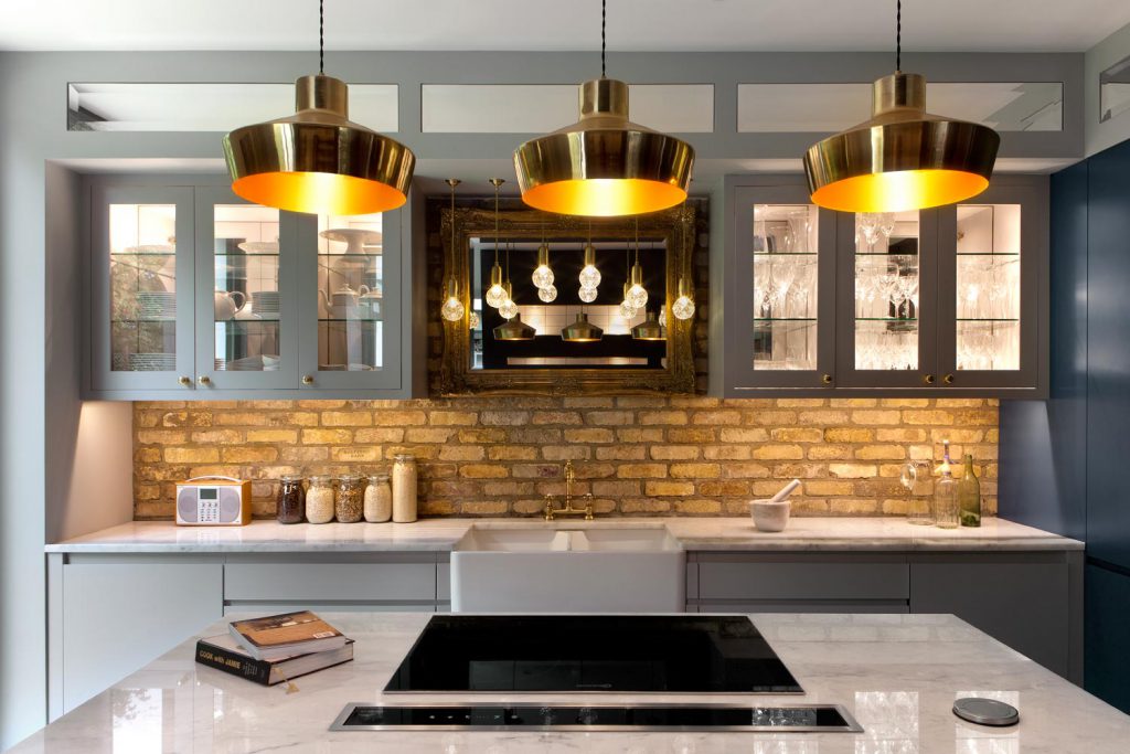 Brass pendants hang in a row of three above the kitchen island