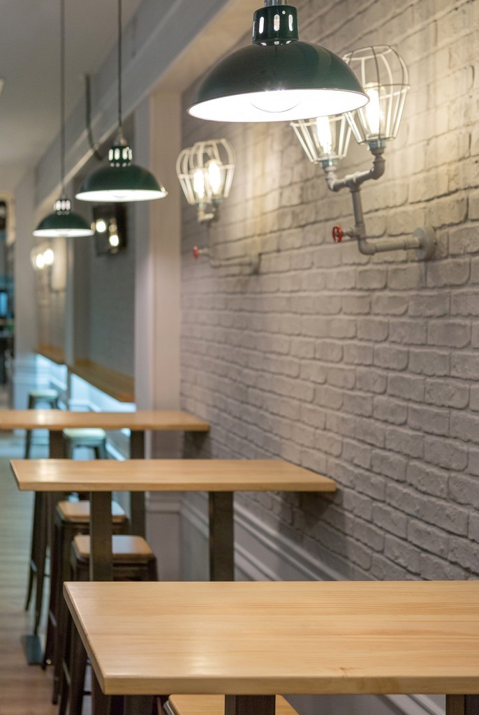 The exposed brick walls of this cáfe is gently illuminated by Osson pendant light from Mullan Lighting