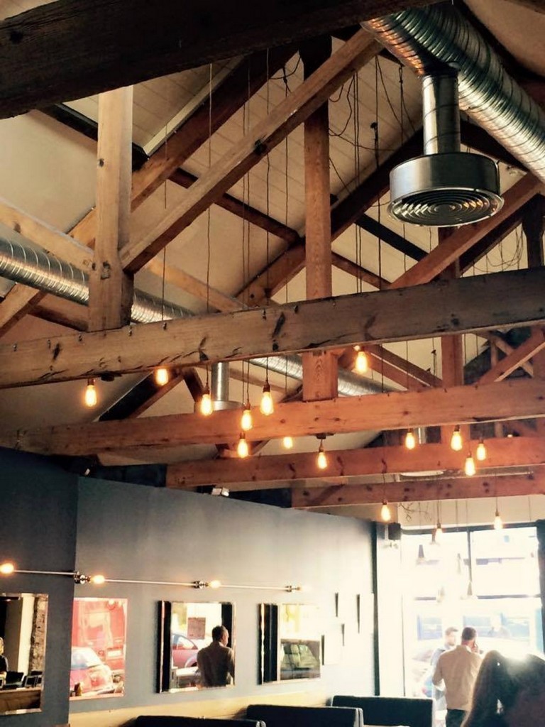 Lighting fixtures that feature an exposed bulb are a growing interior trend. These industrial lighting fixtures are elegantly suspended from the rafters of this restaurant. 