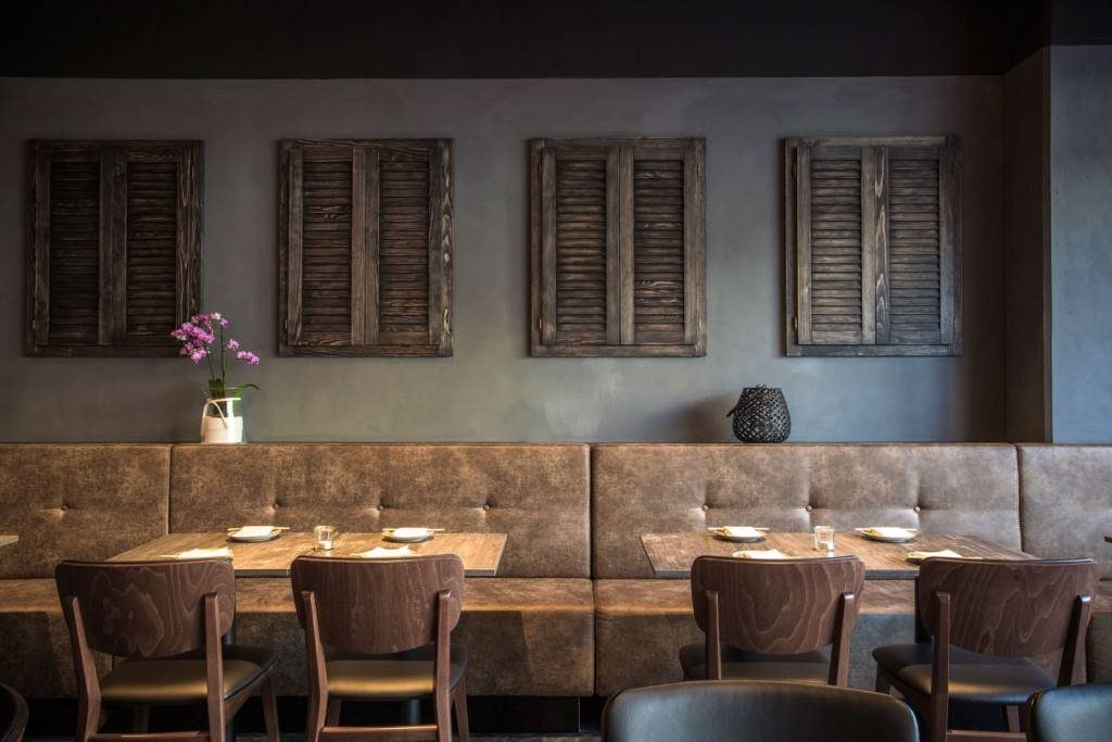 Aged leather and a distressed grey-painted wall create a familiar inviting setting within this industrial restaurant