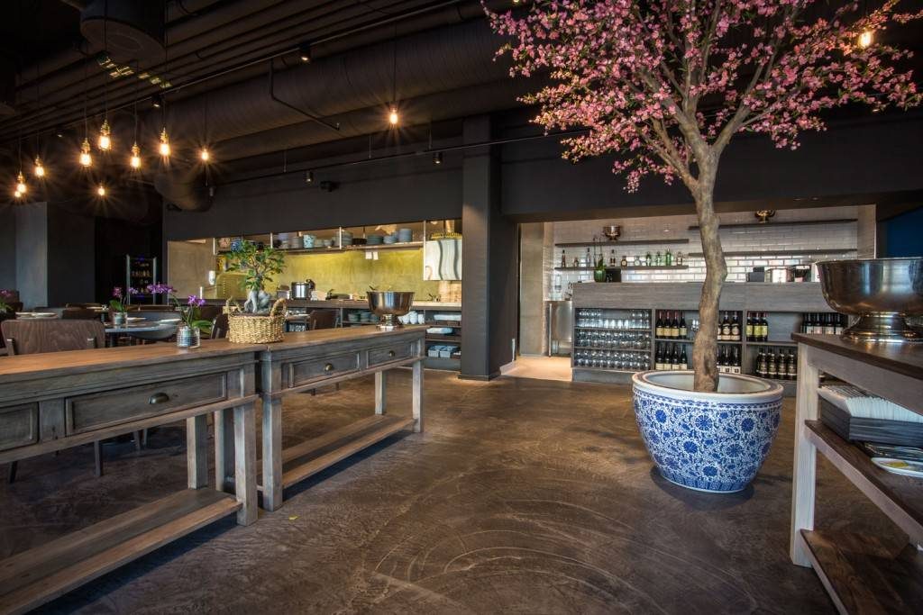 Two large, distressed console tables help establish an entrance hallway to this open and industrial restaurant